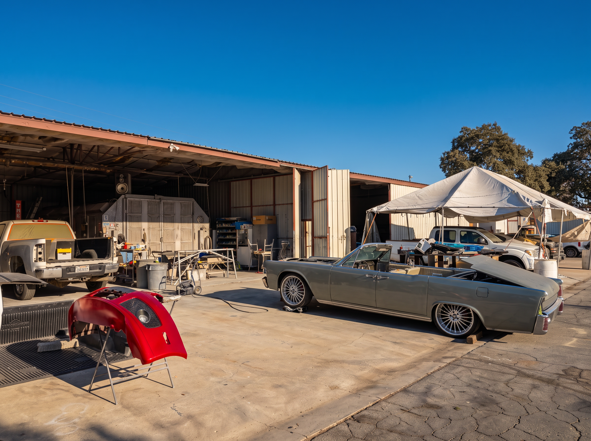 LTP Auto Body shop yard in Paso Robles with a classic convertible in primer and a freshly painted red bumper